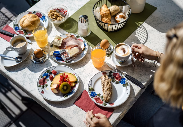 Frühstückstisch im Hotelrestaurant Ochsengarten Auf dem Tisch stehen Frühstücksteller, Kaffee, Saft, Brot, Croissants und Obst.