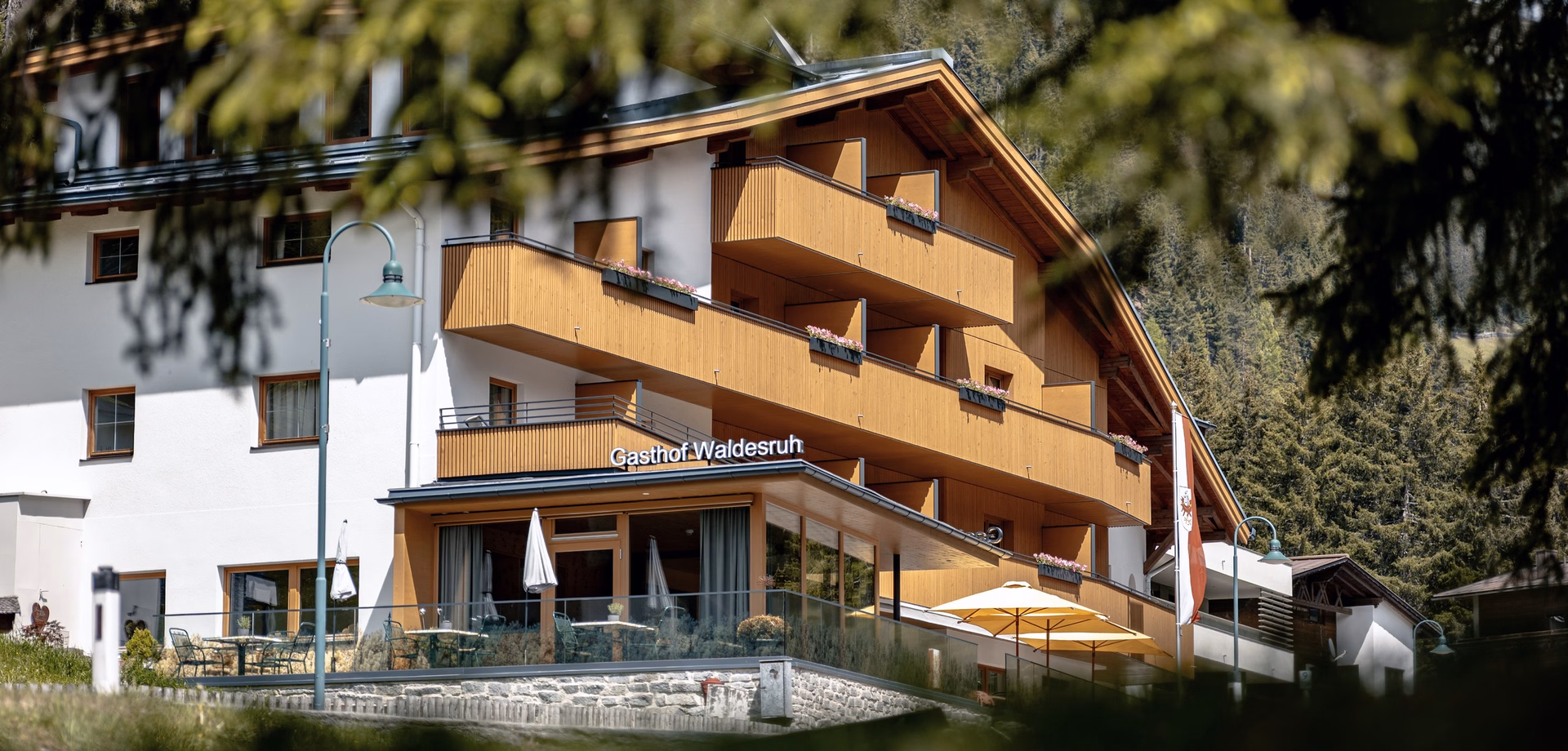 Exterior view of Hotel Waldesruh with wooden balconies and a terrace in front of the building.